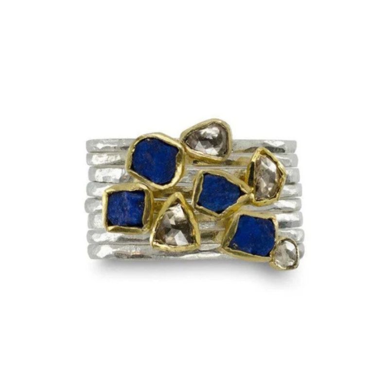 A stacked set of fine hammered silver rings with a small rough diamond or blue lapis lazuli on each band, set in a thin gold surround.