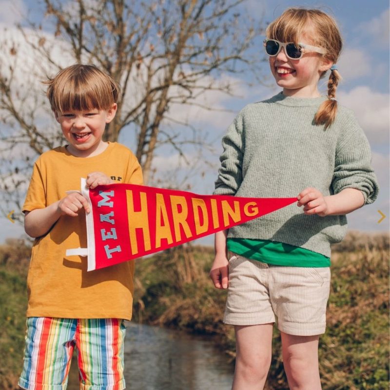 Two children holding up  a personalised pennant flag