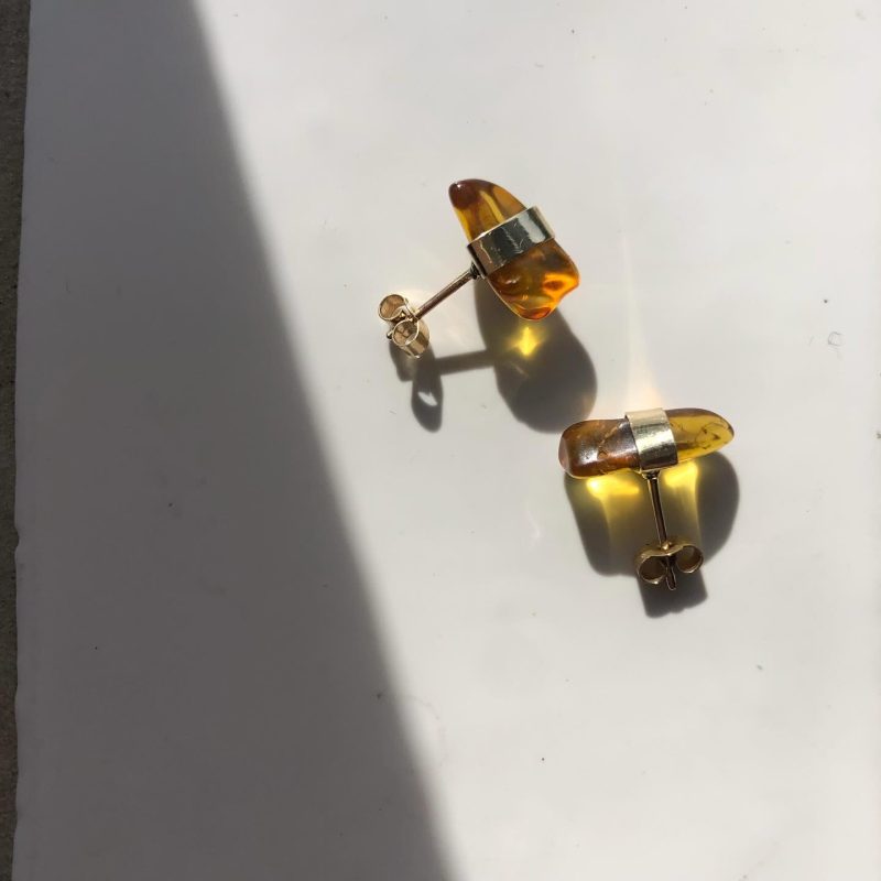 A pair of amber earrings with gold background on a white background