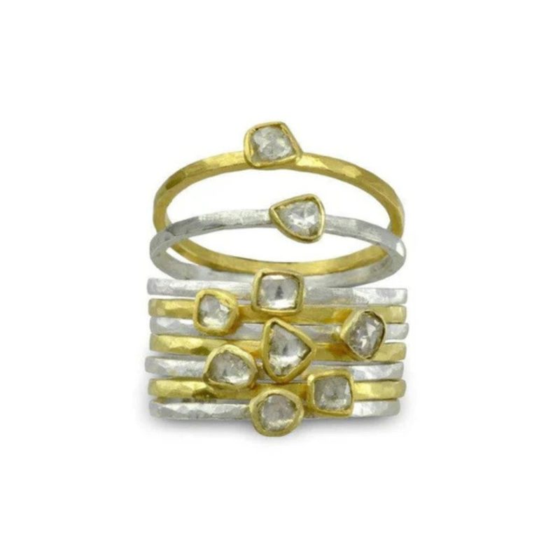 a stacked set of fine hammered gold and silver rings with a small rough diamond on each set in a thin gold surround.
