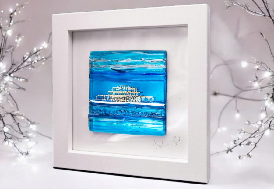 A textured glass tile in shades of aqua and turquoise with an abstract image of Brighton West Pier in shiny 22ct gold