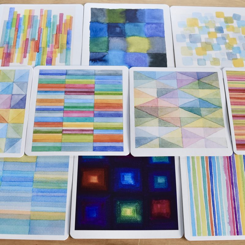 A set of abstract watercolour 148mm square cards with rounded corners. The paintings are simple geometric compositions in bright colours with lots of turquoise, blue, orange, green and pink.