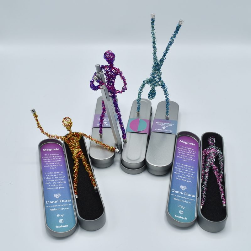 Magnetic wire figures in different colours and poses, some standing on the metal tins that they come in