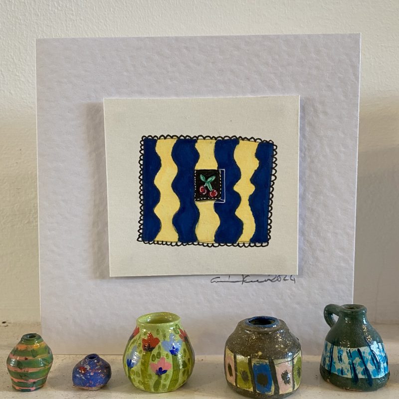 Hand painted card depicting small patterned square with decorative border with miniature painted ceramic pots in foreground