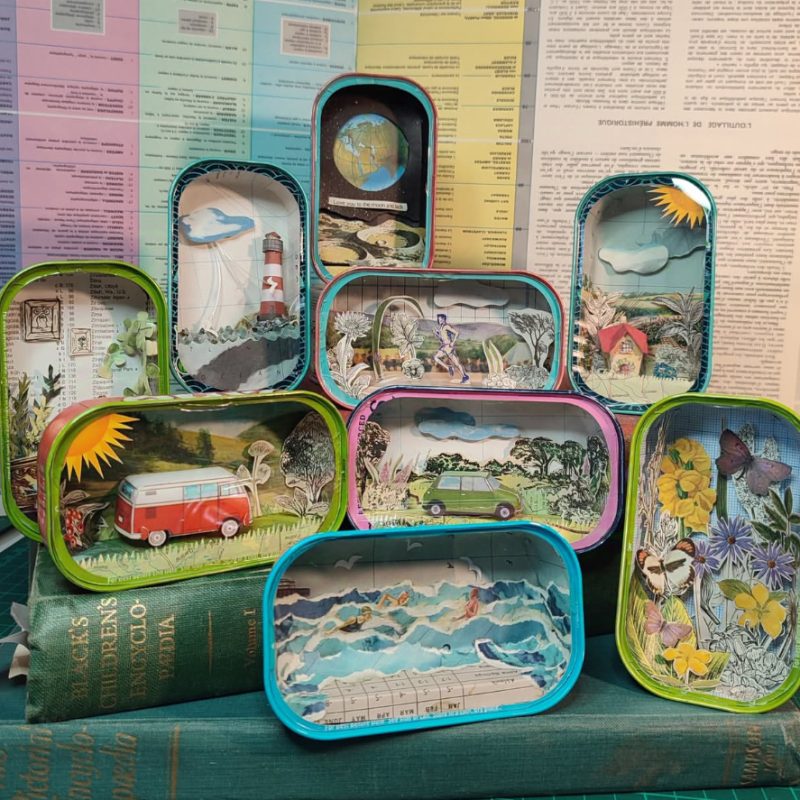 Lots of sardine cans with different dioramas inside . All hand cut in paper .