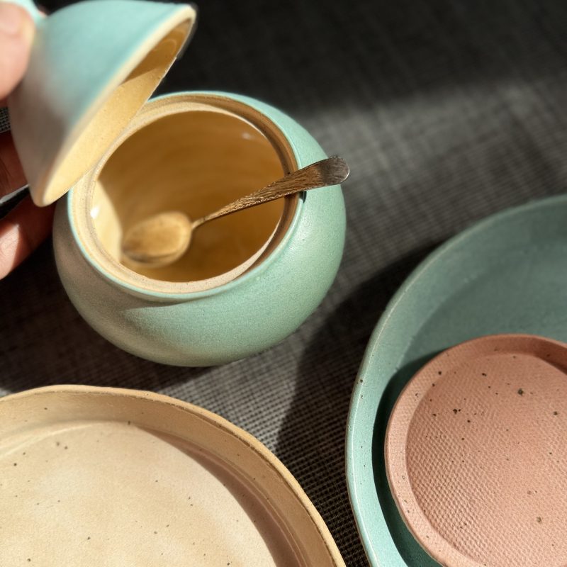 Stoneware ceramic lidded pots and plates in soft colours including a bowl and plates
