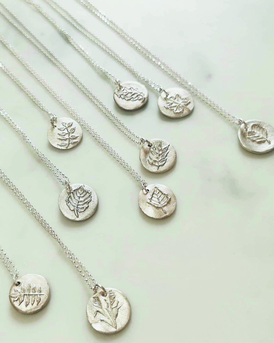 Fine and sterling silver circular pendant with hand carved leaf shapes in the centre