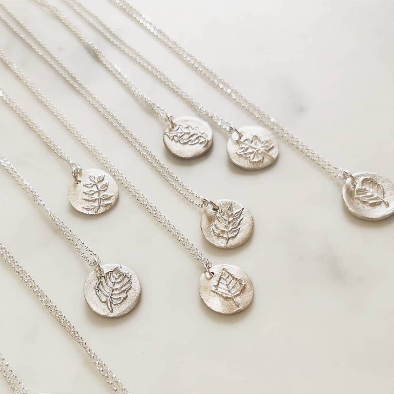 Fine and sterling silver circular pendant with hand carved leaf shapes in the centre