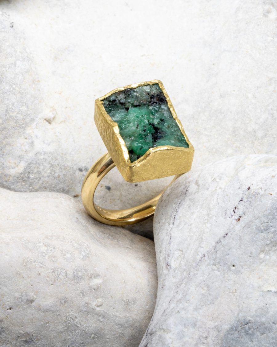 Ring with a rectangular rough cut emerald in a textured matt gold mount on a D section band
