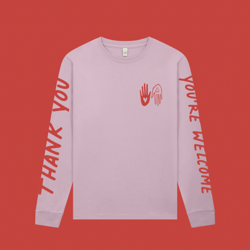 Long sleeved pink t shirt with red screen printing graphics. 'Thank you' along one sleeve and 'You're welcome' along the other. Two hands with hearts are printed in small as a pocket print. 