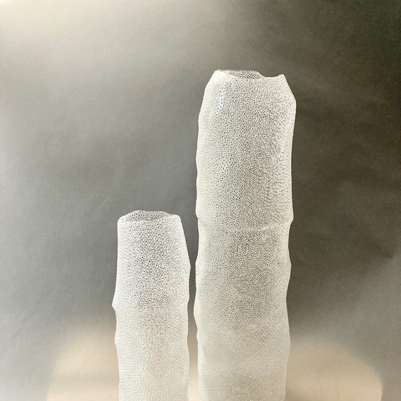 Single use plastic water bottles refashioned into ethereal and highly detailed vessels, punctured with hundreds of holes, evocative of sea coral