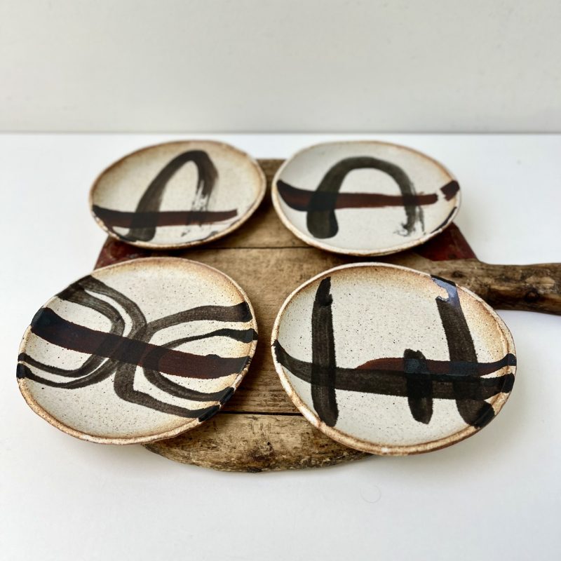 Four handmade ceramic plates which have been handpainted