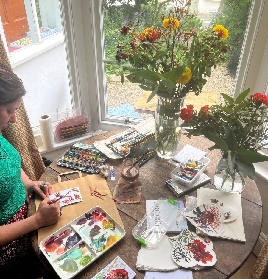 Artist painting blooms at the table in the bay window