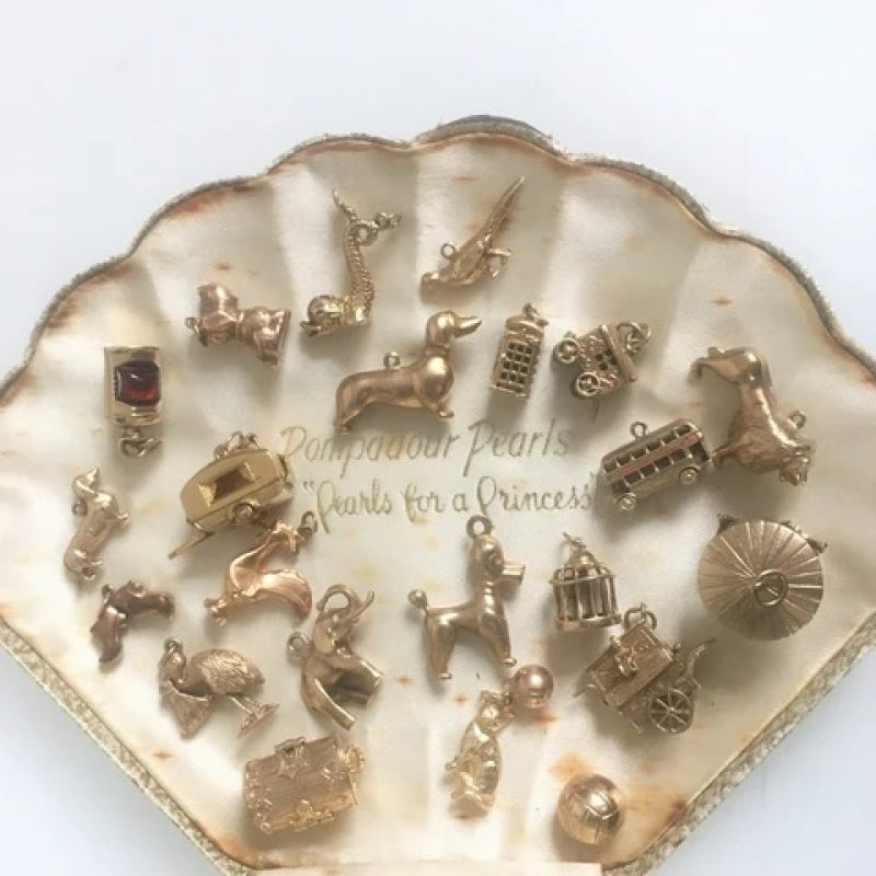 A jewellery box shaped like a clam shell contacting a mix of vintage jewellery charms