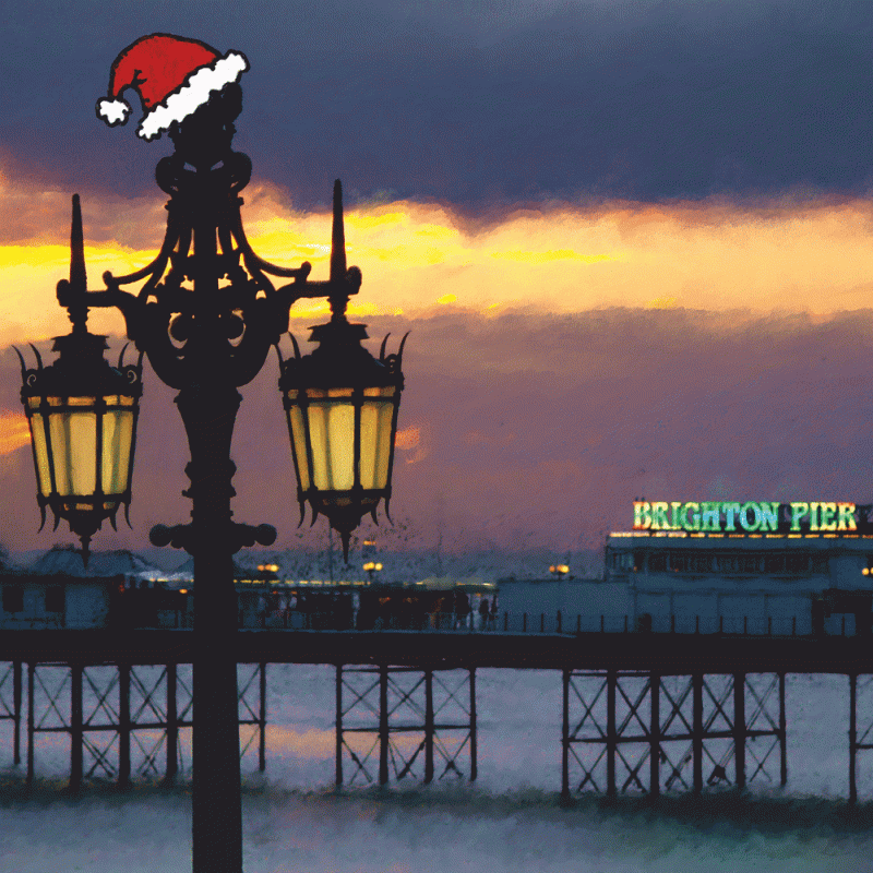Streaked sunset over the Brighton Palace Pier with an iconic Kemptown Lamp wearing a Santa hat