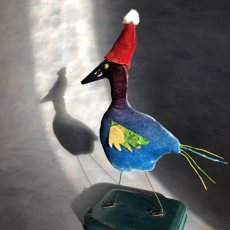 Bird made of velvet with recycled aluminium can for wings and beak , and telephone wire as a tail .