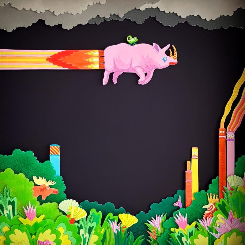A hand-drawn and colour illustrated diorama featuring a rhinoceros rocketing over a verdant landscape, made of layers of Giclée prints mounted in a box frame.