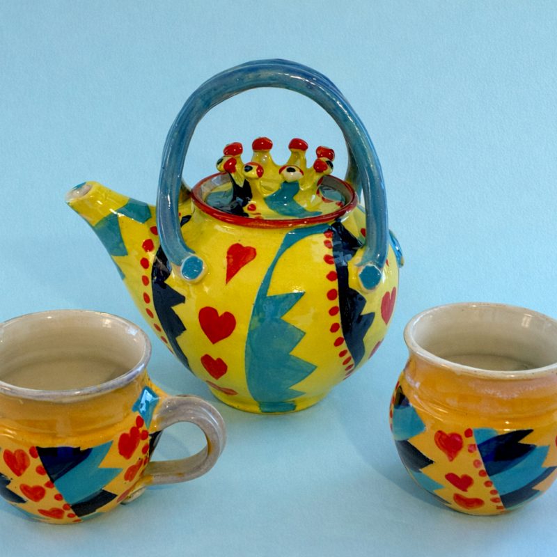 Brightly coloured ceramic teapot with matching ceramic mugs