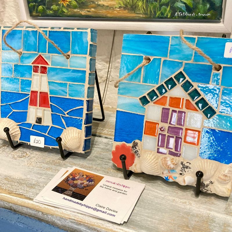 Square mosaics depicting colourful beach huts with a blue sky and sea background