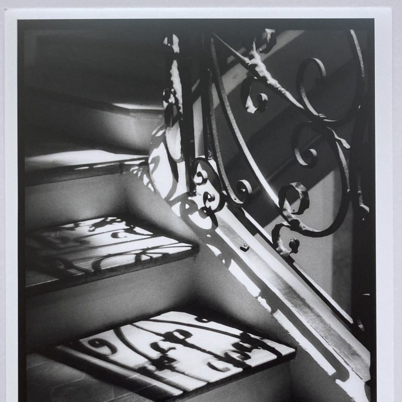 A decorative staircase and handrail with the sun creating strong shadows across it.