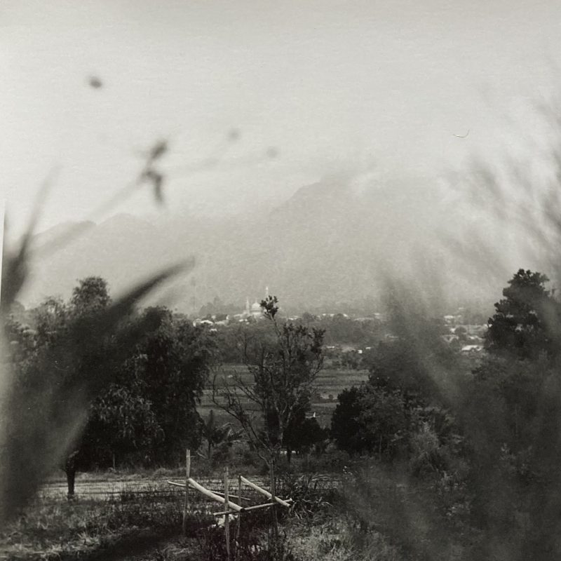 A landscape across fields and a mosque, looking towards Mount Rinjani in Indonesia.