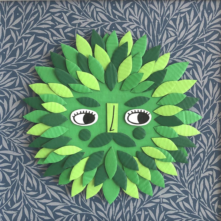 A Green Man made from hand painted cardboard and mounted on leafy paper