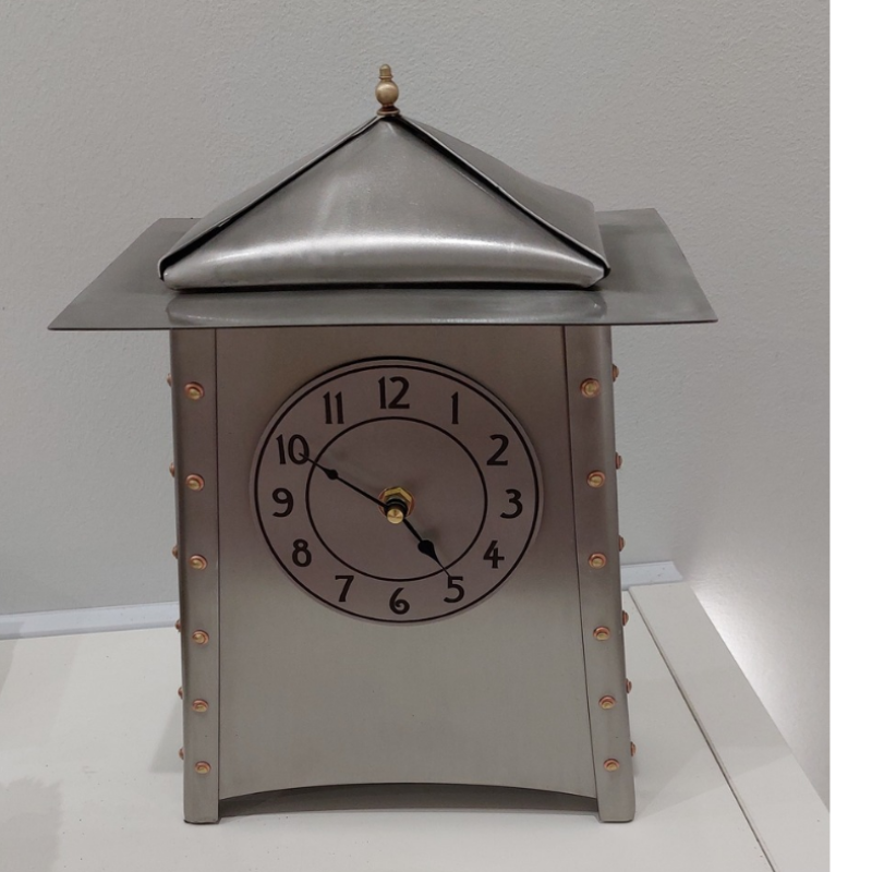 A stainless steel clock in a unique style with copper rivets and a black dial face.