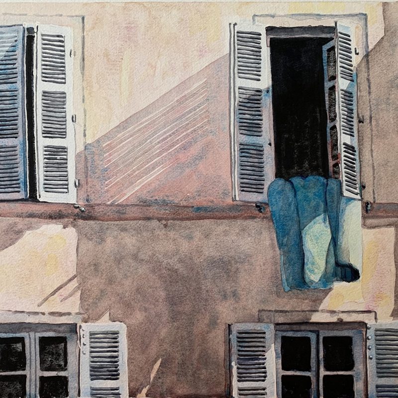 A window with shutters and a quilt hanging out