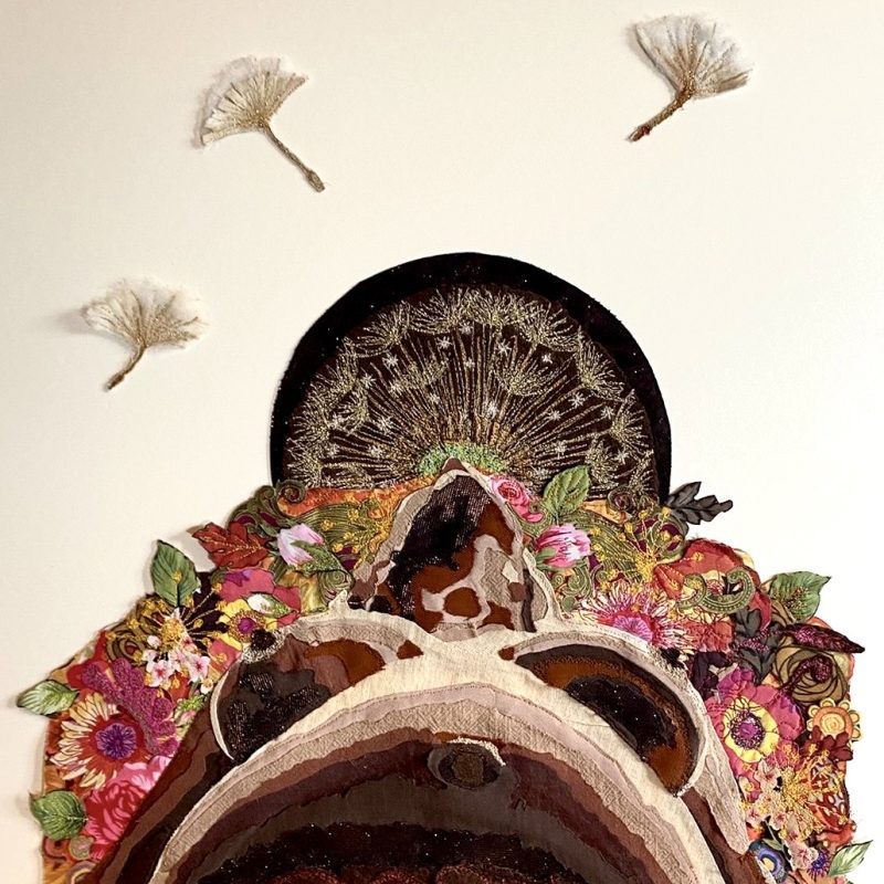 A large textile piece with added machine embroidery of a heavily pregnant woman yielding to her bodies innate strength to birth