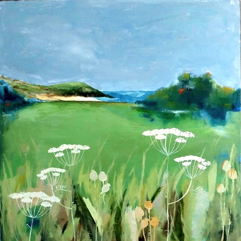 A spring landscape with blue sky, view towards the sea and green hills with spring flowers in the foreground