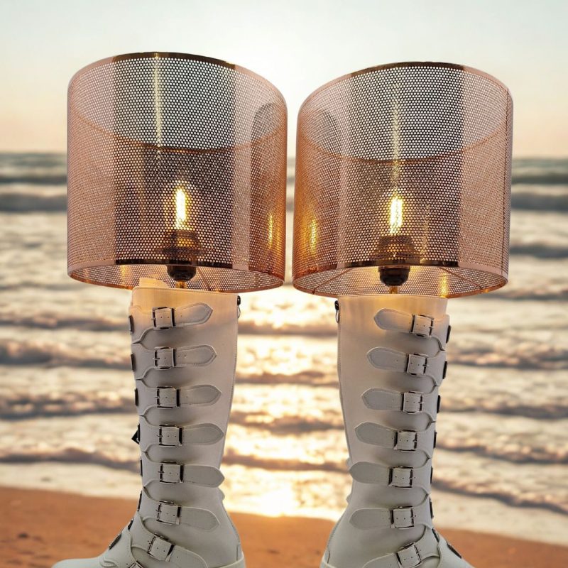A pair of white tall white boots with lots of buckles transformed into unique lightng with bulbs and light shades.