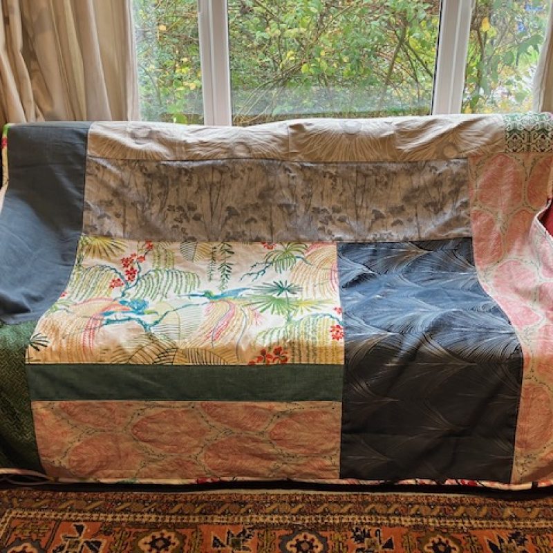 Large handmade quilt using pieces of cotton reminants . 