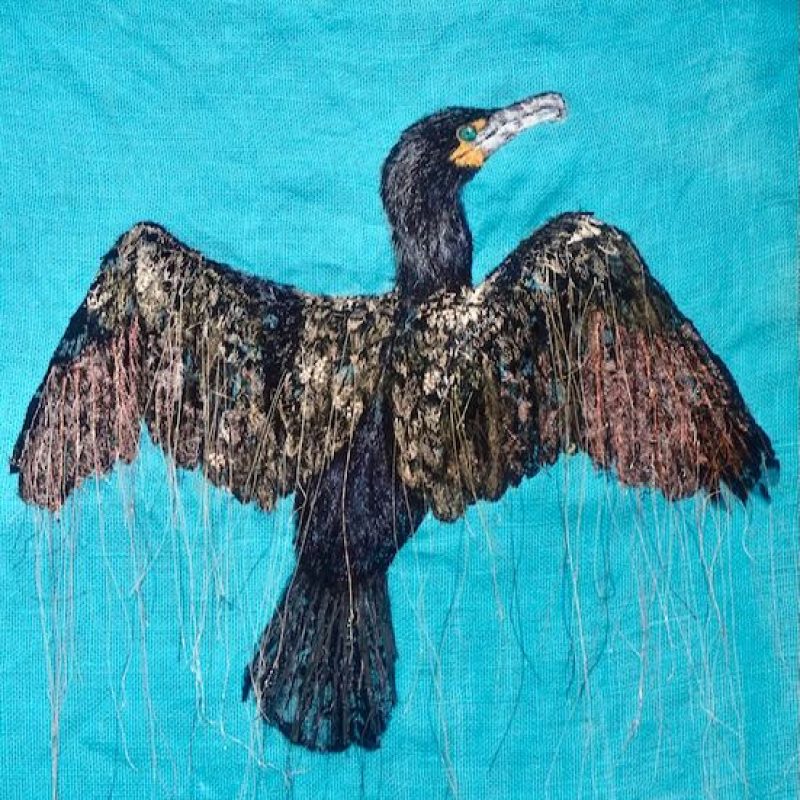 A large cormorant with outstretched wings. Black stitch on a blue background 