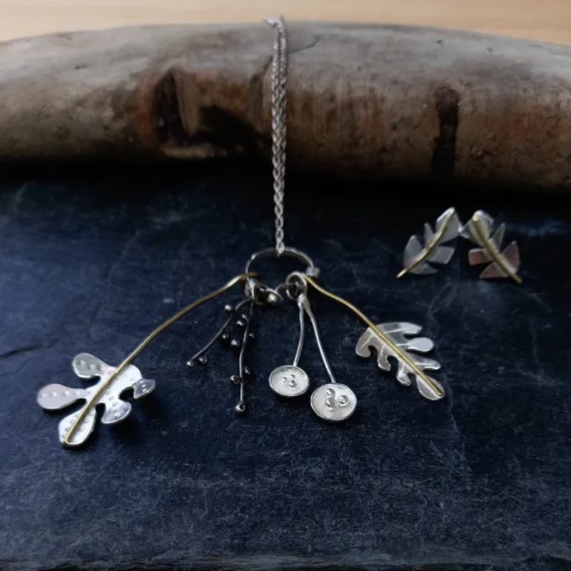 Silver necklace and earrings with leaf shapes cut out.