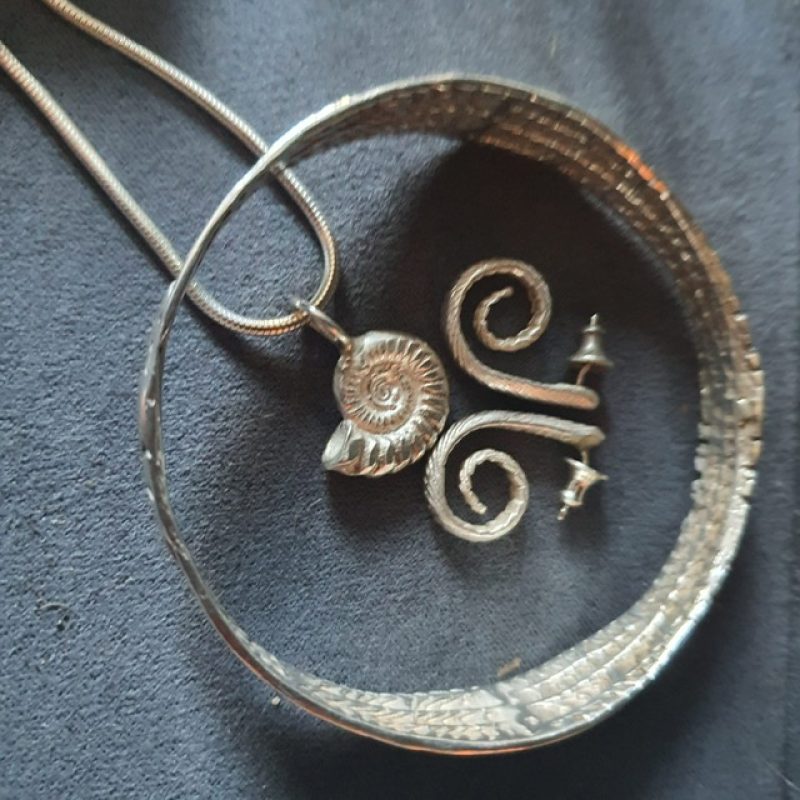 Silver Earrings in the shape of a curled leaf, an ammonite shaped pendant and a curled leaf bracelet, 