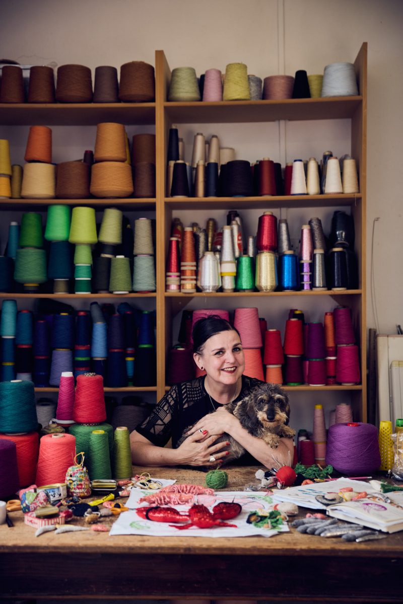 A portrait of Kate Jenkins in her studio with her miniature wire haired dachshund Dilys 
