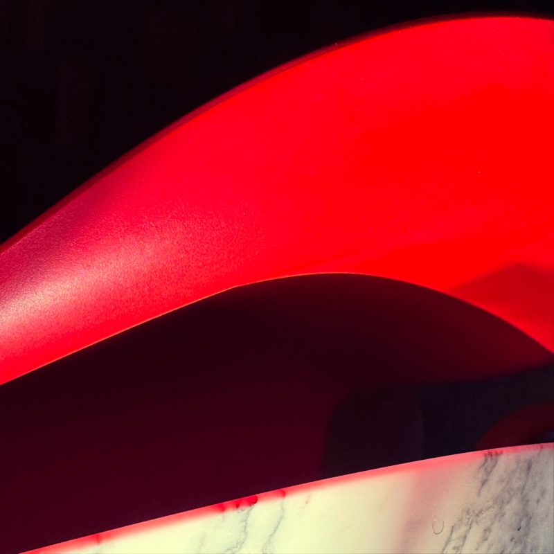 An abstraction of a white marble Eero Saarinen table and a red Verner Panton chair with fragments of sun and shade.