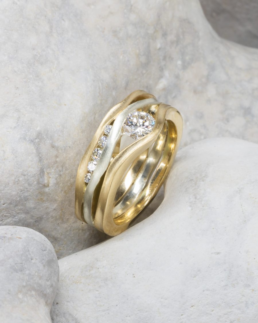 A ring made from three square wires that have been hammered on the side to make them undulating. Diamonds of various sizes are set between the bands. the outer two are yellow gold and the inner one is white gold.