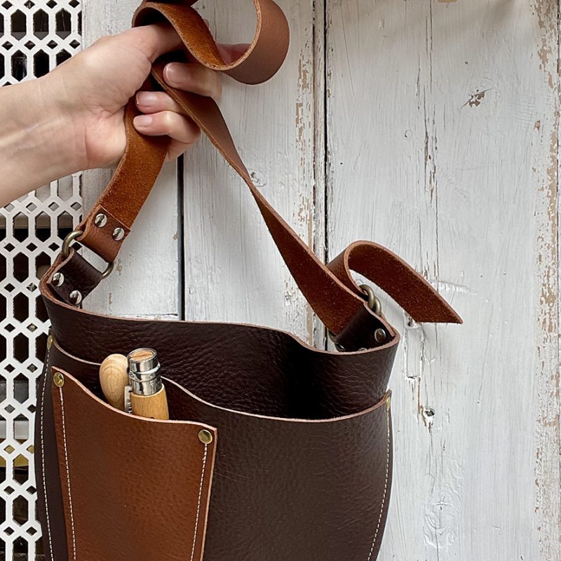 Handmade leather tool pouch and belt in two shades of brown, The pouch is u shaped with a pocket on the front for small tools.