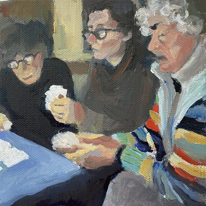 Three people playing cards at a blue table