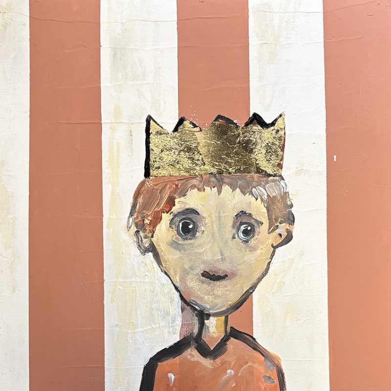 A boy wearing a party crown in front of stripy wallpaper of pink and white