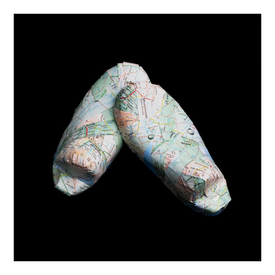 Against a black background are two shoe like forms.  The tip of one rests against the other.  the forms are constructed from strips of a map of Somalia,.  Greens and blues from the map are the predominant colours.