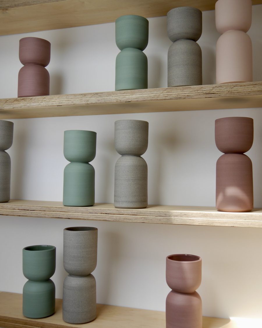 Collection of coloured vases displayed on a series of shelves