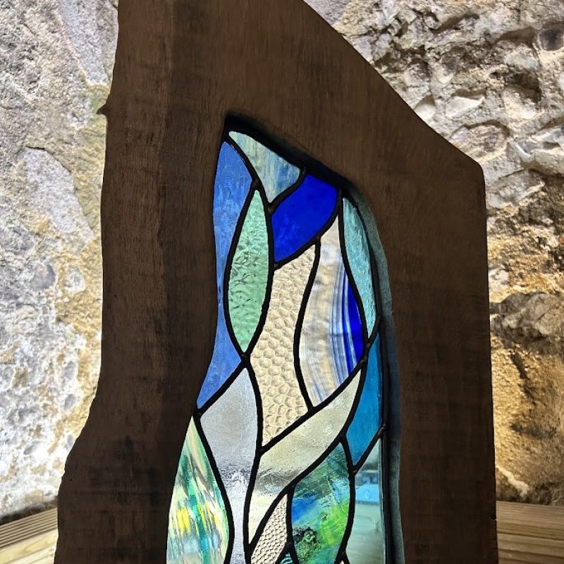 A beautiful glass work in blues surrounded by a natural wooden frame