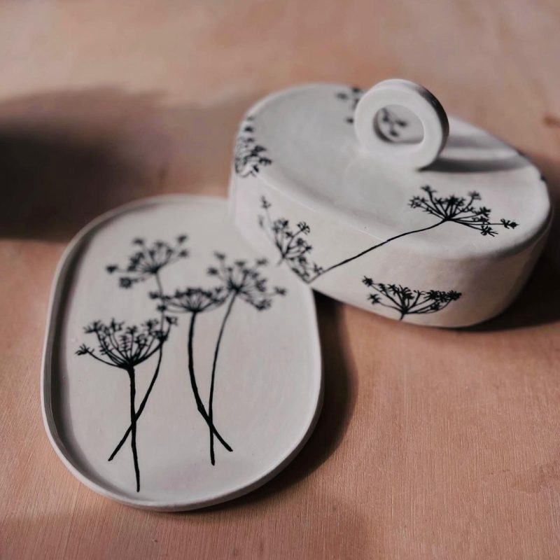 A ceramic butter dish decorated with black painted cow parsley