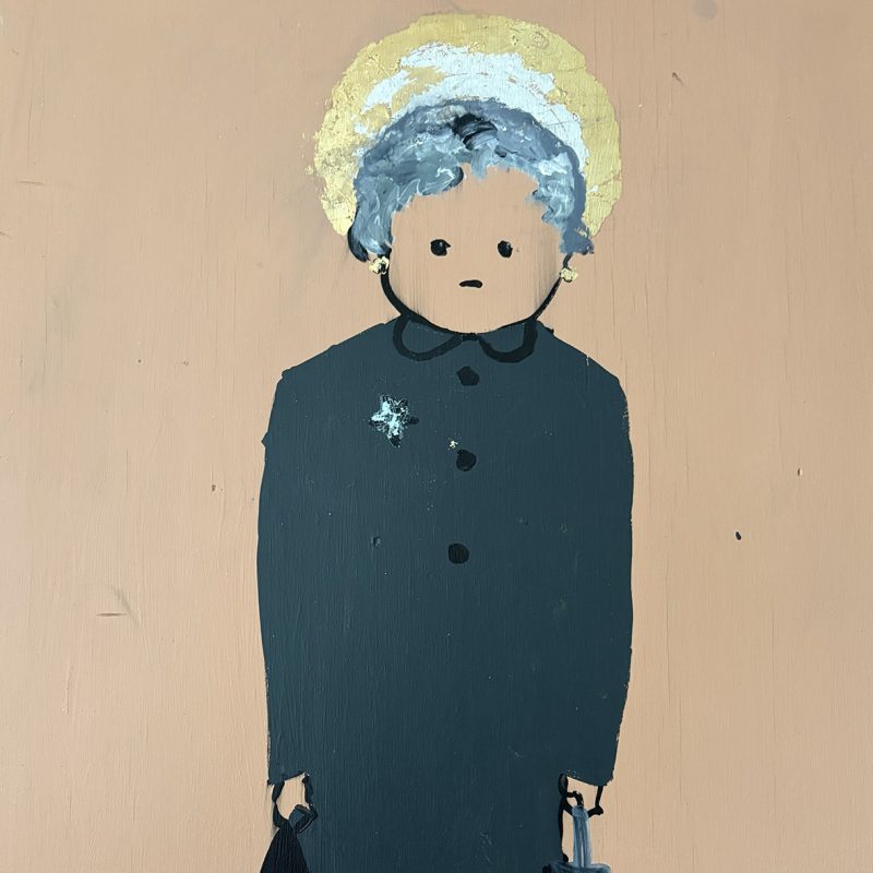 A grey haired woman stands in a long coat with heavy shopping bags in both hands on a dusty pink background.