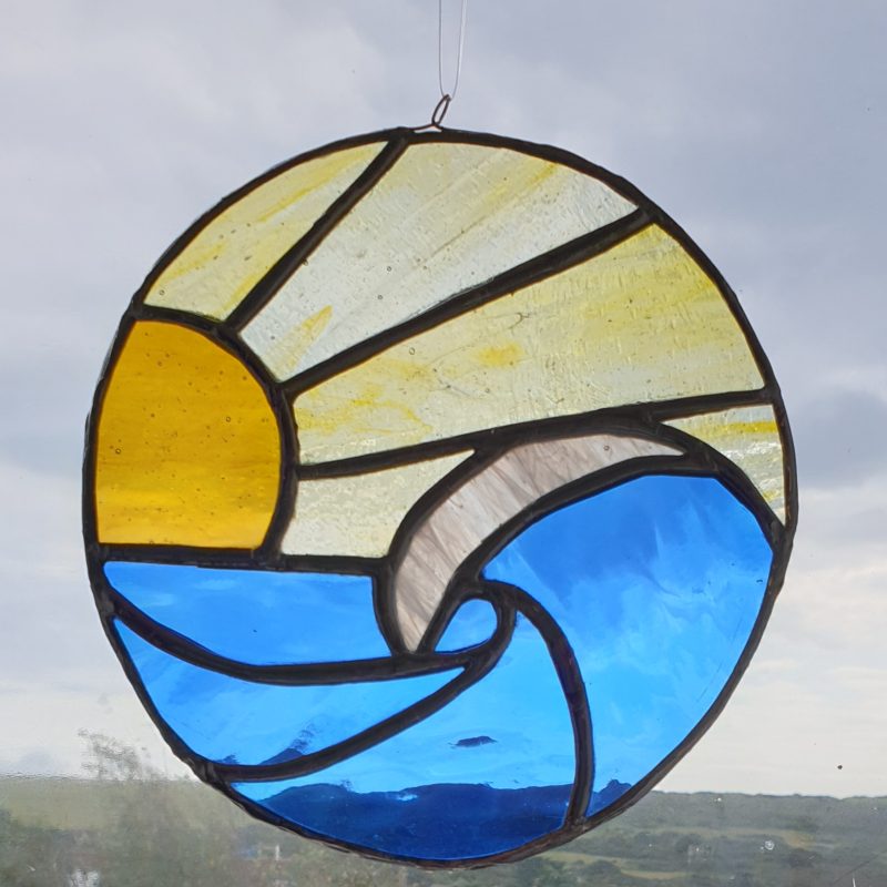 A stained glass window hanger of a wave at sunset