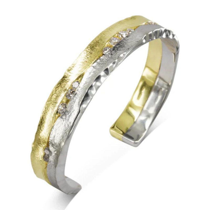 Hammered half gold and half silver cuff bangle, hammered on the side to give it undulating edge, set with a scatter of diamonds in between the two halves.