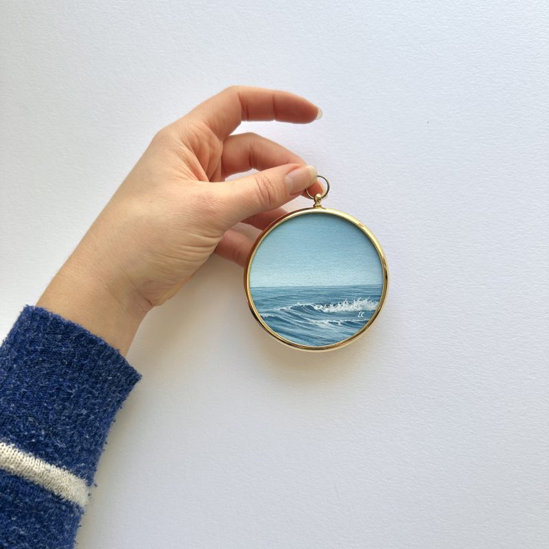 A small seascape painting in a round second-hand vintage-style brass frame