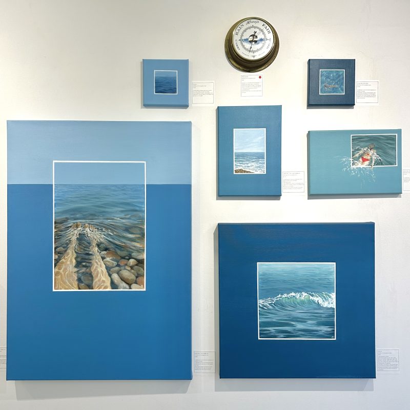 A gallery-wall of paintings of the sea and people enjoying the water